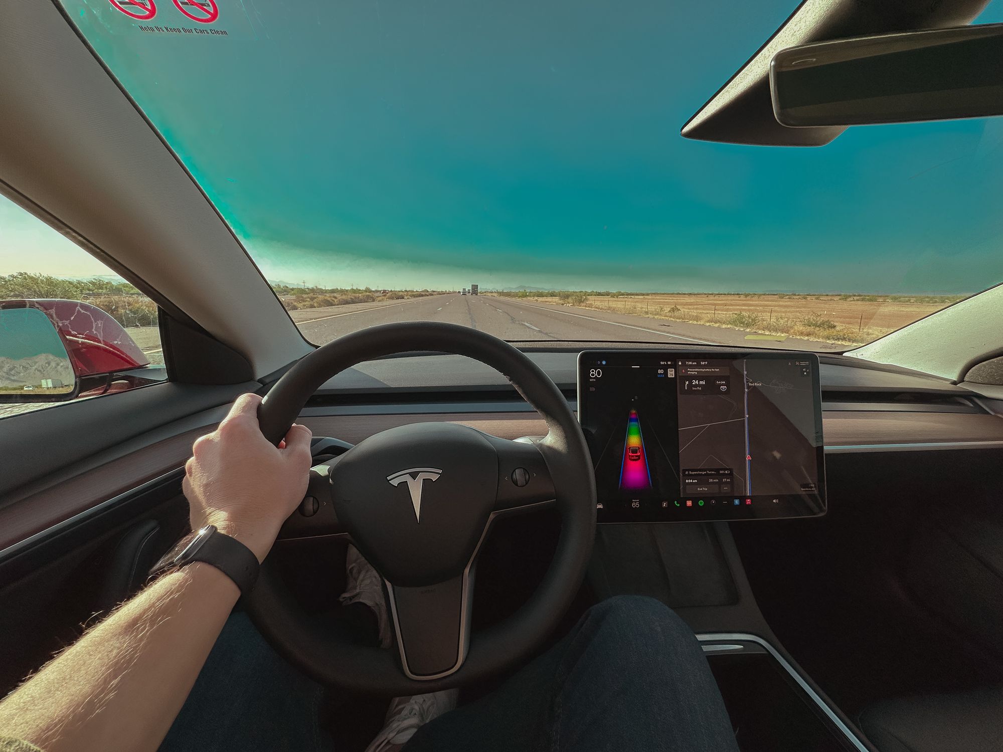 Wide angle photo of a driver driving a Tesla Model 3 on Basic Autopilot