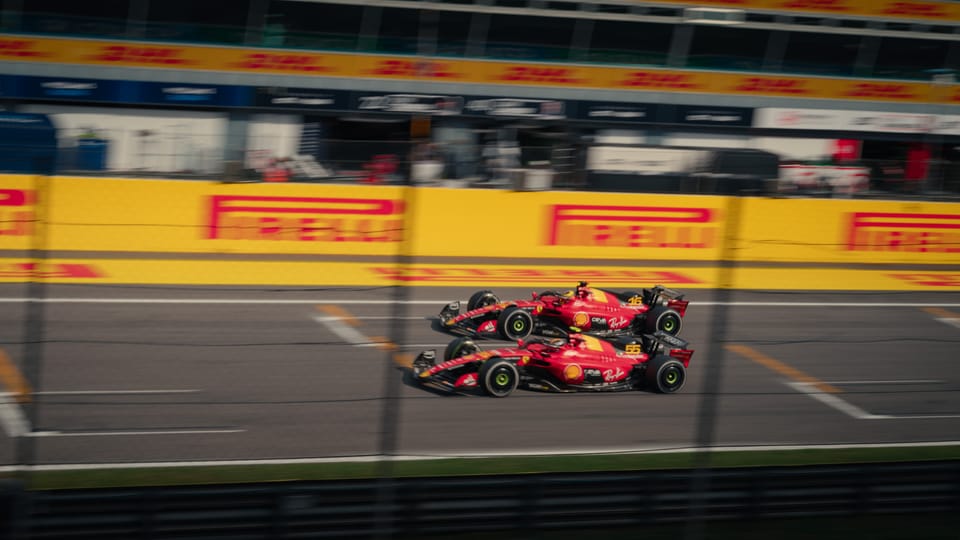 Panning photo of two 2023 Ferrari F1 cars racing side by at Monza on the main straight.